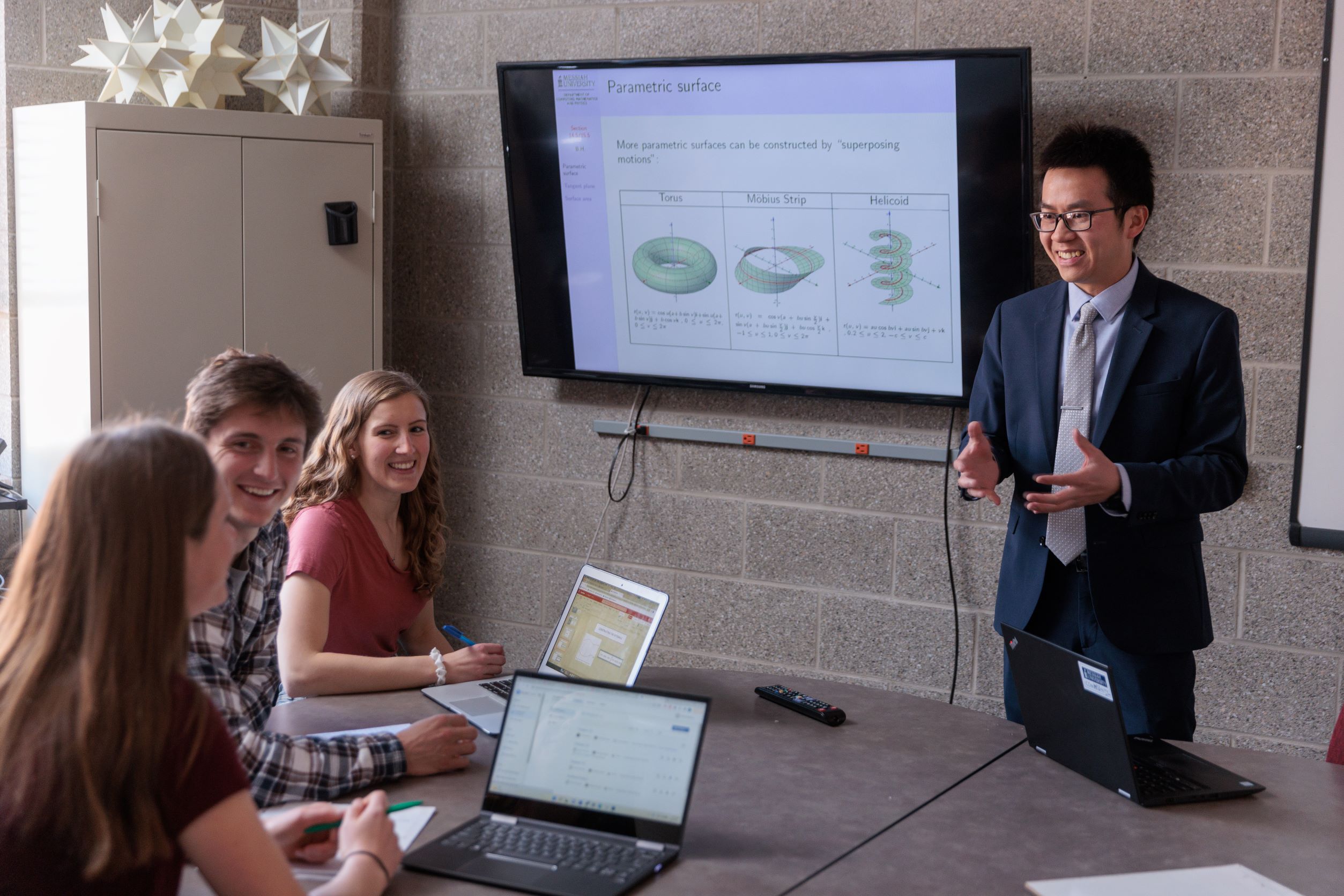 Professor standing in front of three students