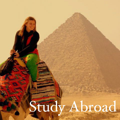 A student sitting on a camel in front of the Pyramids of Giza.