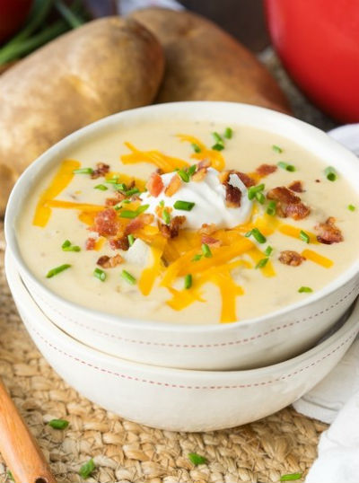 A bowl of baked potato soup with cheese and sour cream on top.
