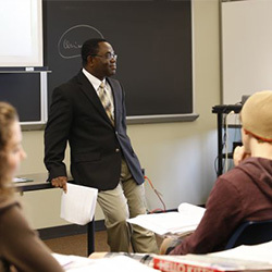 Teacher Education Program instructor in front of a black board.