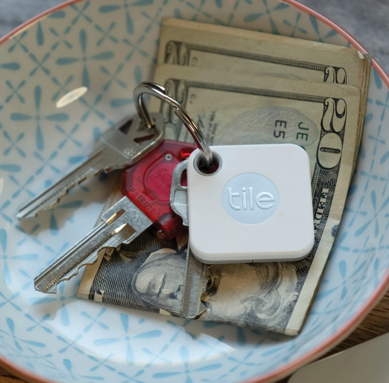 A tile shaped keychain is next to keys and money.