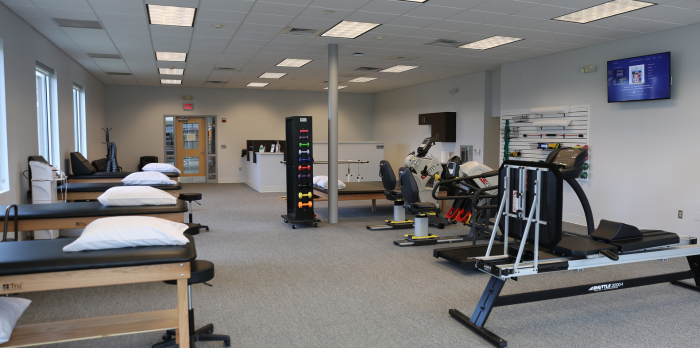 An image of the inside of a physical therapy clinic is shown. There are medical tables and various medical equipment.