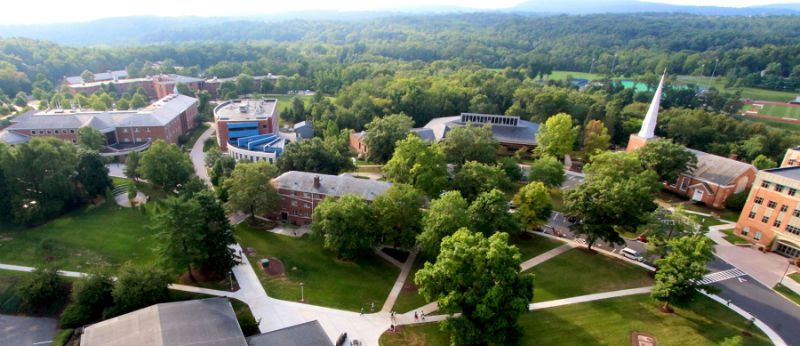 An aerial view of campus shows academic buildings, trees, pathways and mountains.