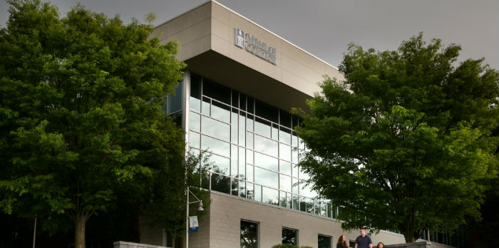 A large building with glass windows is shown with two green trees on either side.