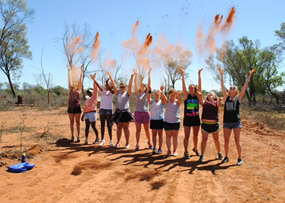 A group picture of students throwing dirt into the air during their study abroad.