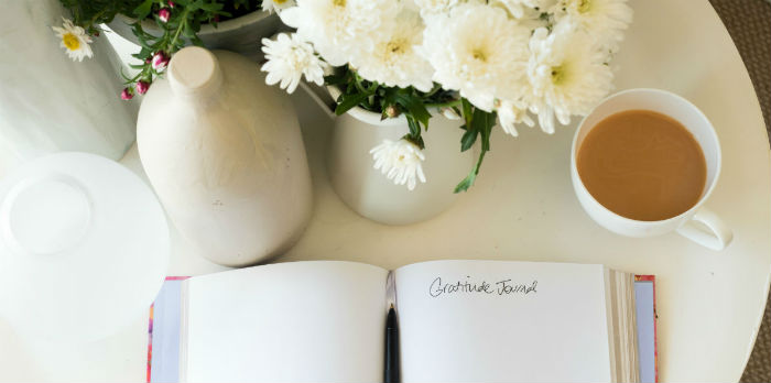 Gratitude journal next to coffee and flowers