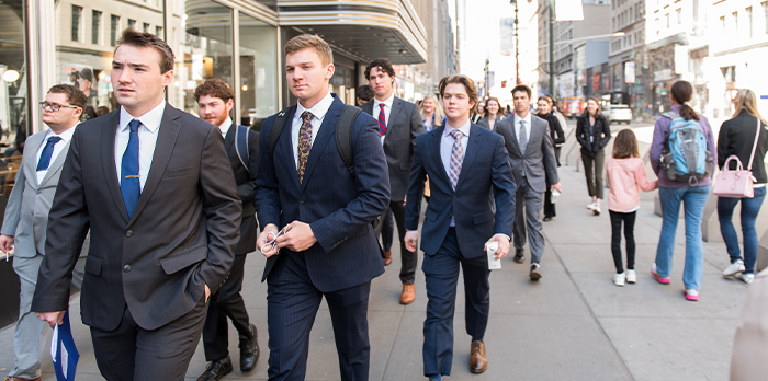 Students wearing business attire walk around the city.