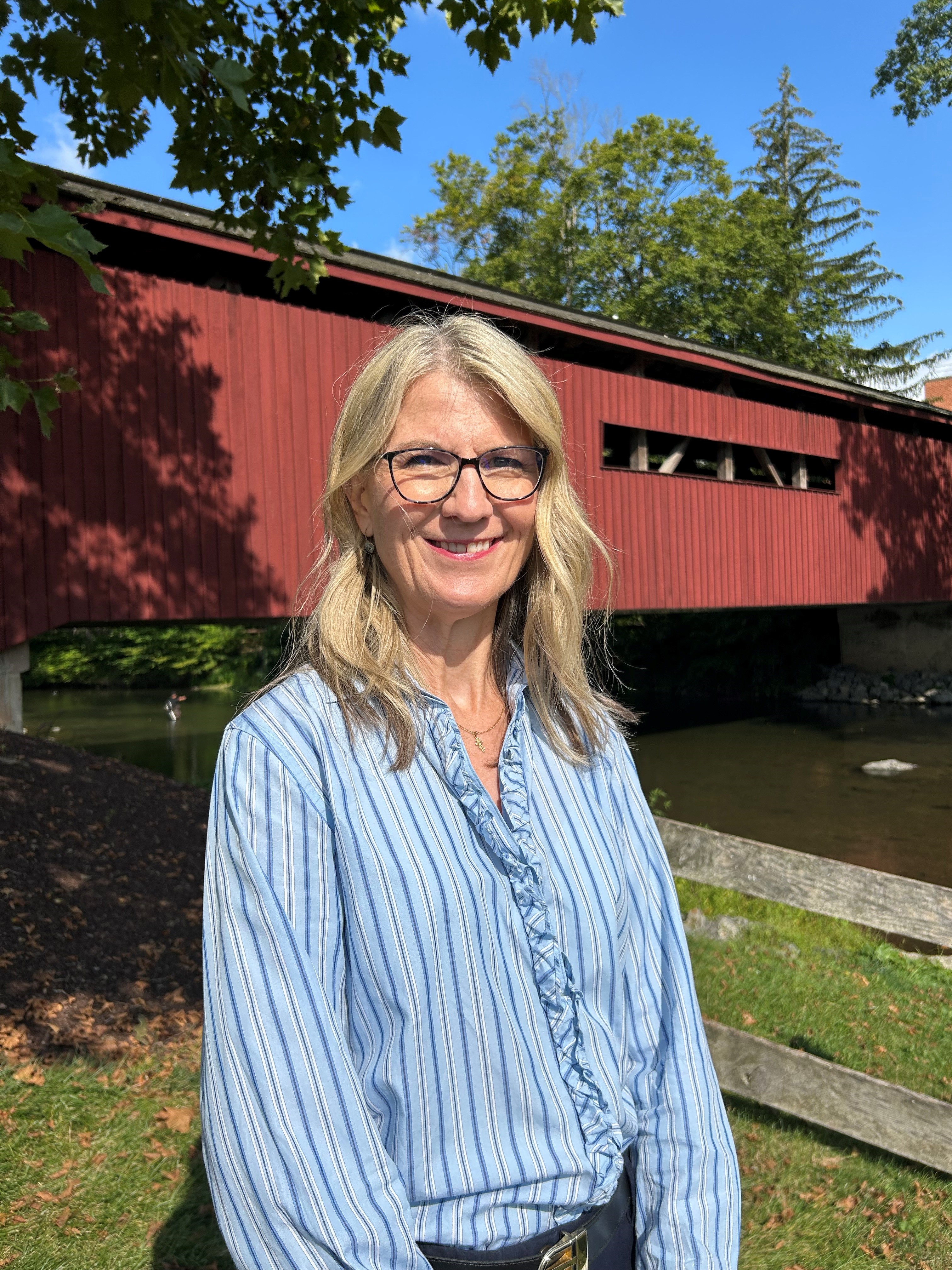 woman in front of covered bridge, smiling