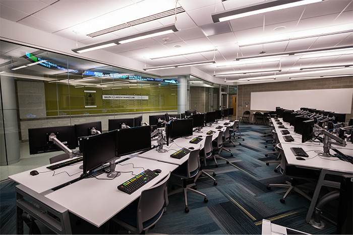 A row of computers sits on a table inside the Larsen Finance Lab.