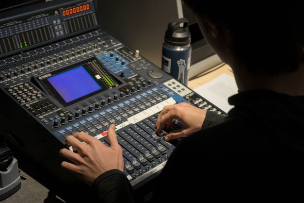 Someone's hands operate a switchboard, sliding buttons up to make adjustments.