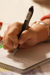A hand uses a pen to write in a book
