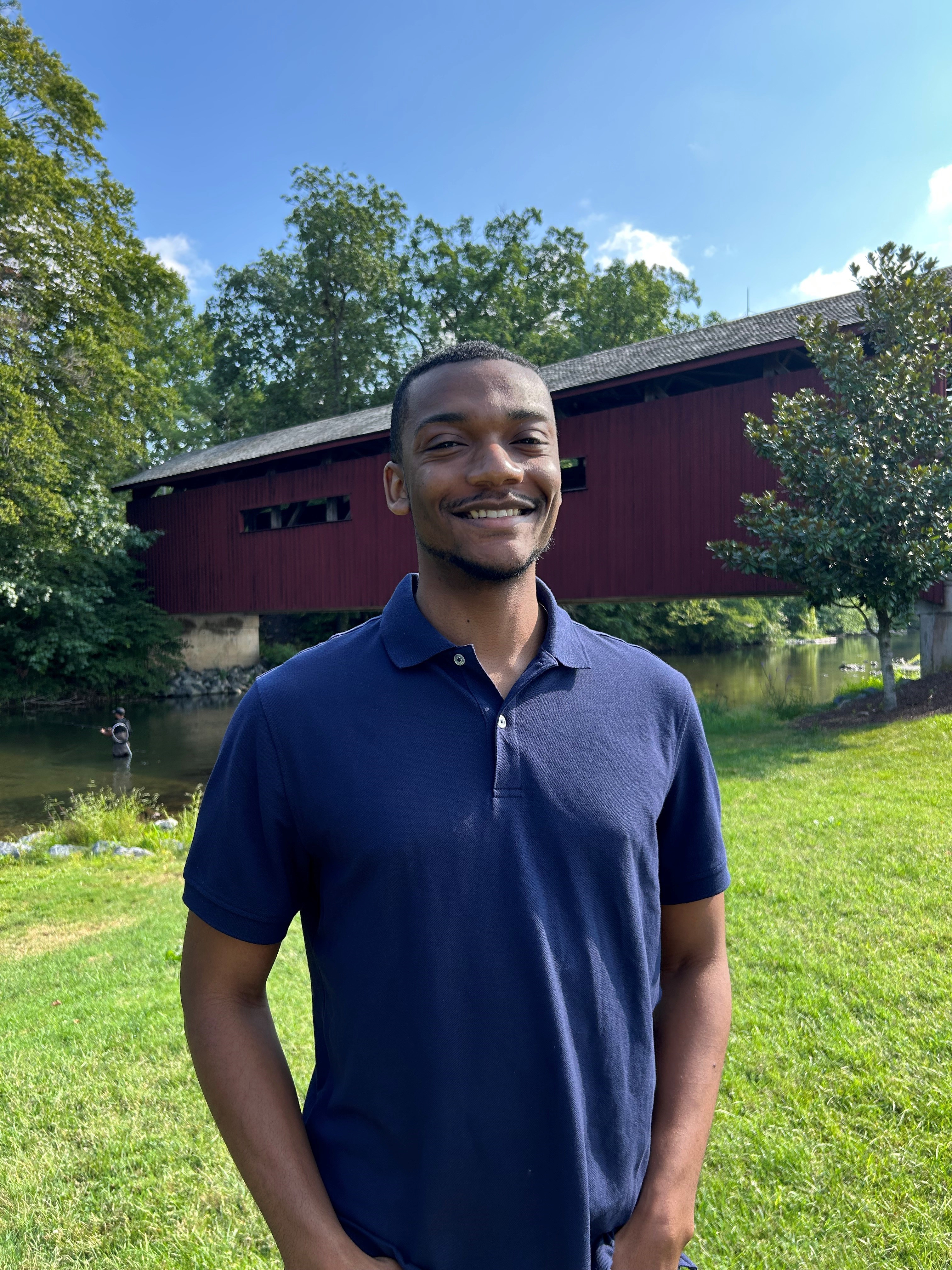 Man standing in front of covered bridge, smiling