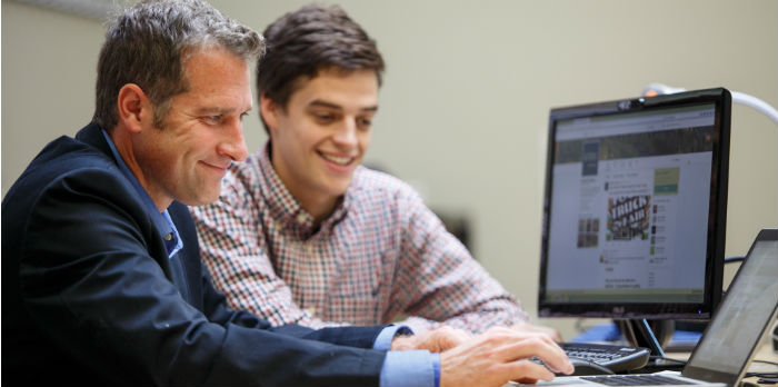 Professor of marketing teaching student on laptop