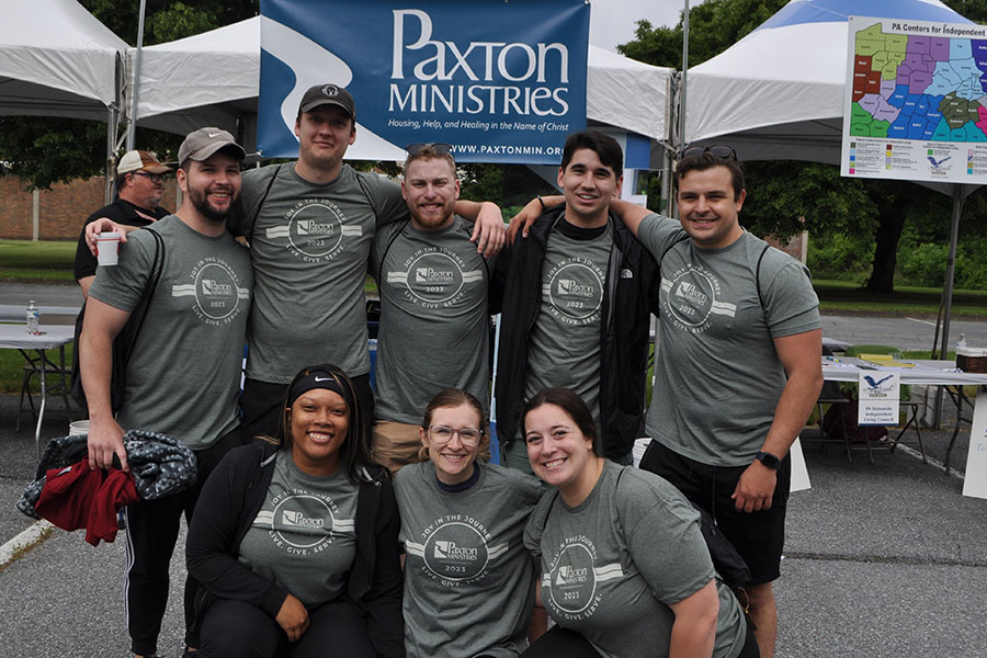 A group of students stands in from of a paxton ministries sign