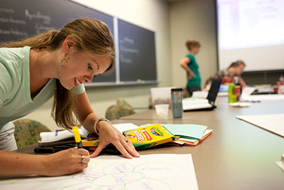 Adult student working with markers making poster