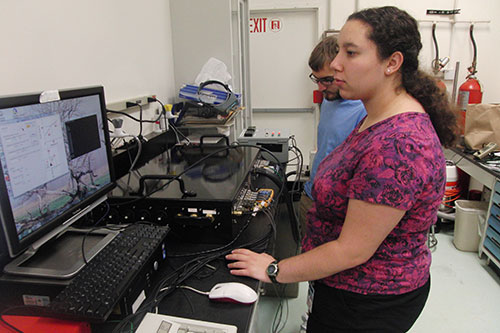 Physics student standing in front of a computer.