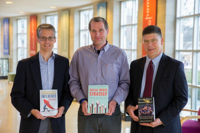 Business professors holding their published book.