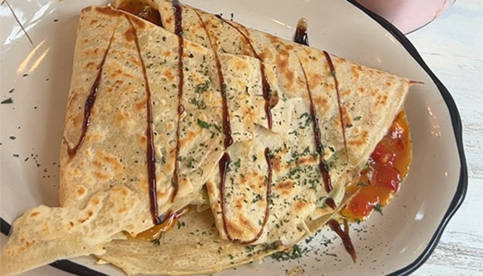 a crepe with vinaigrette drizzled over it sits on a plate