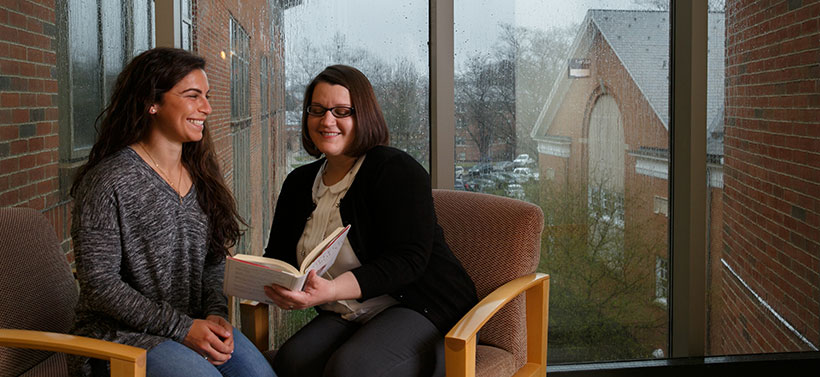 Student and professor looking at book