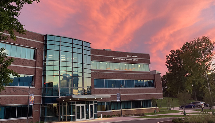the sun sets behind the admissions and welcome center, painting the sky pink