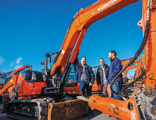 Lucas Messick with his brothers in front of a orange Kubota truck