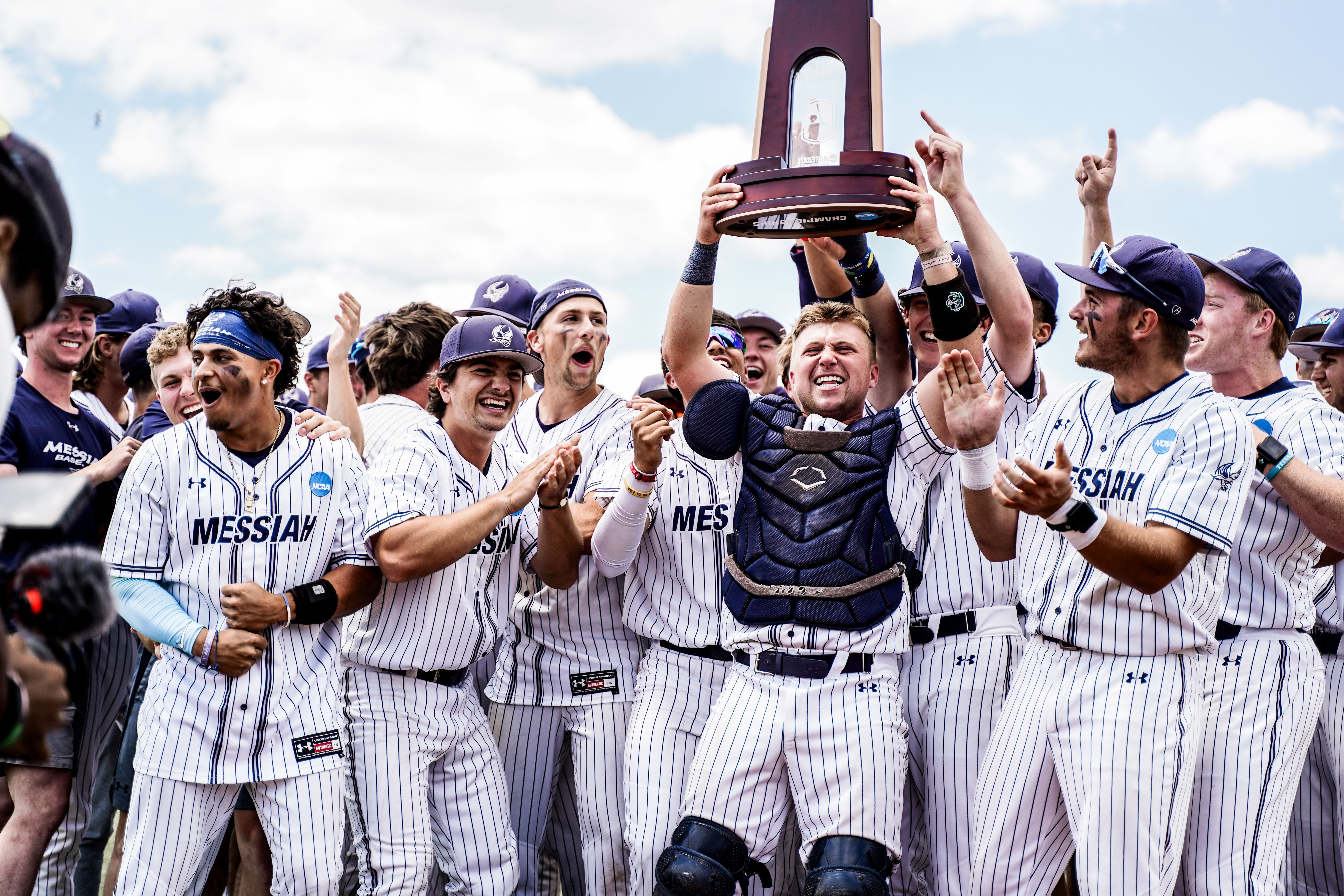 Men's baseball team celebrating win with trophy