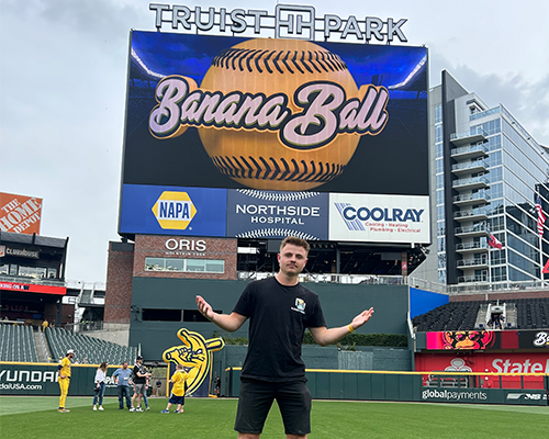 Caleb Kuiken in front of large screen that says "Banana Ball."