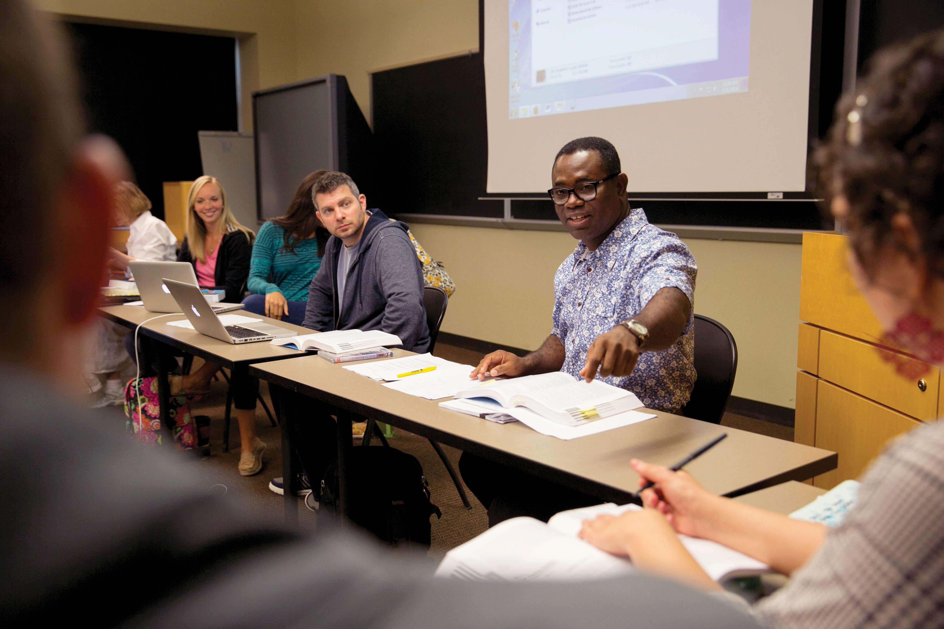 Adult students talking to one another in a classroom.