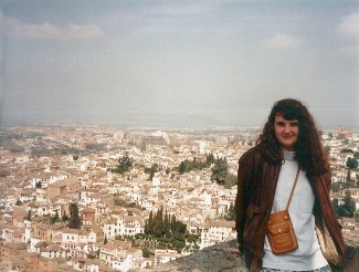 A woman leans against a bridge overlooking a city in Spain.