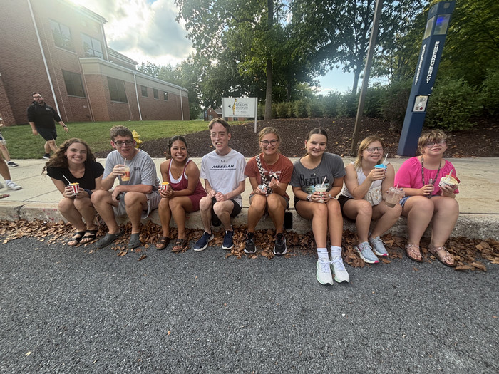 group of students and peer mentors sitting on curb.