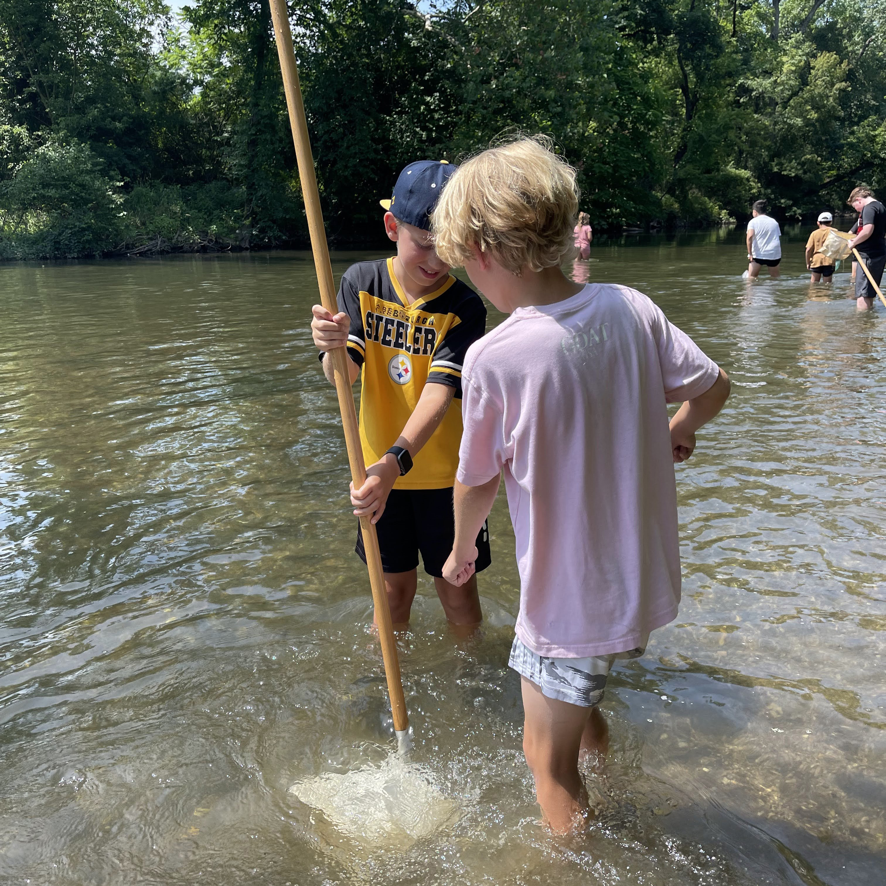 Two children using a net in a creek.