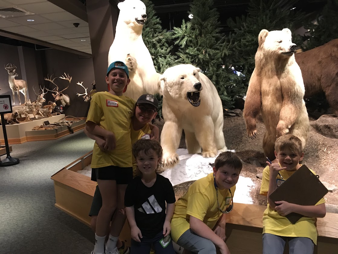 Boys posing in museum in front of polar bears.