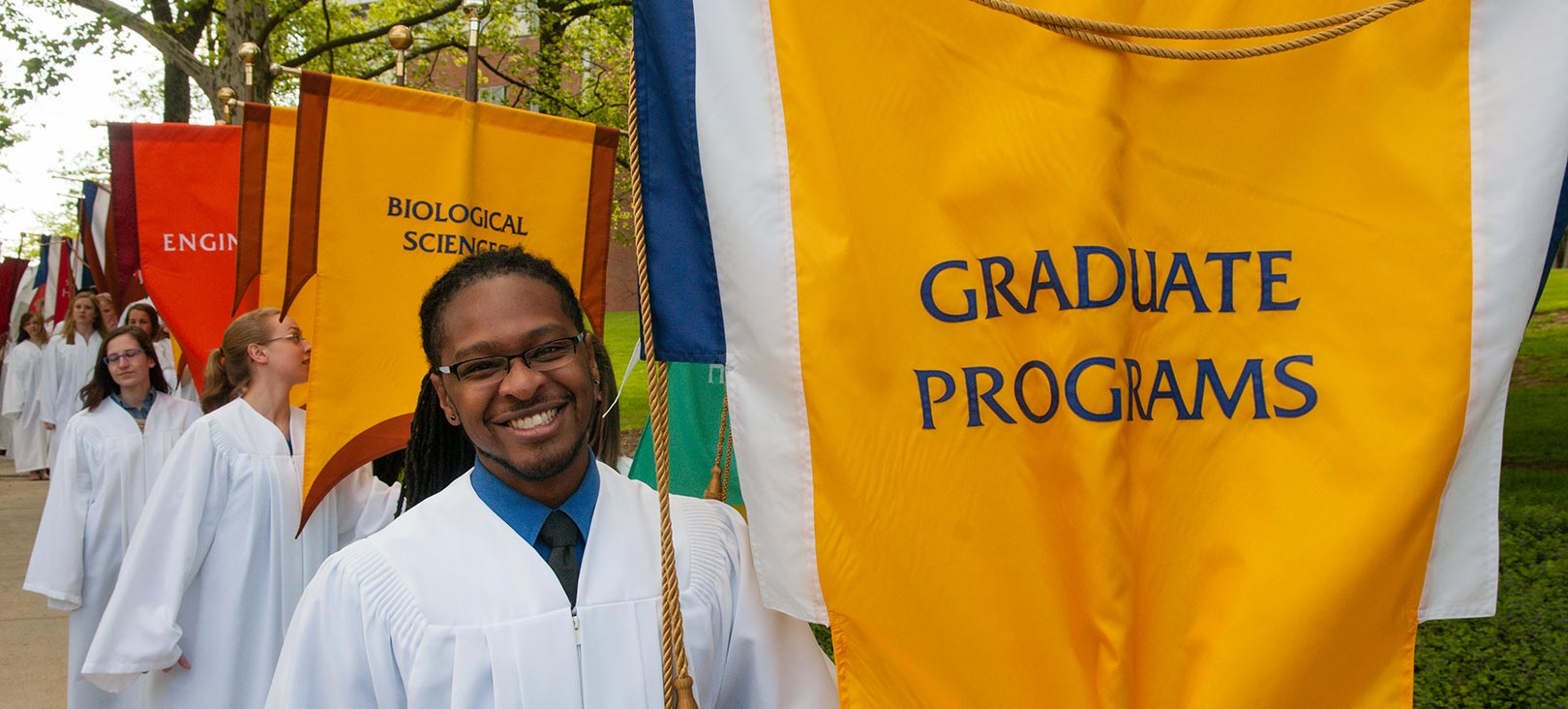 Graduate Programs A male african american student holding up a graduate programs flag.jpg