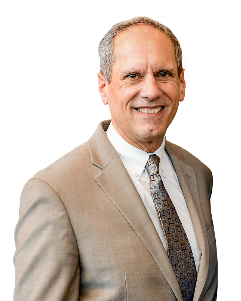 Jon Stuckey headshot of a middle-aged man wearing a beige suit and patterned tie, smiling against a white background.