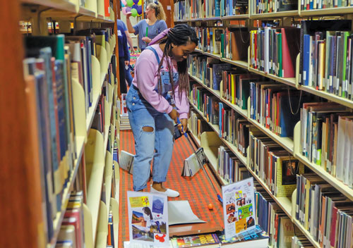 Student walking through library aisle