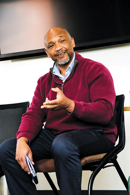 anthony grooms in red sweater, sitting and talking.
