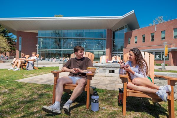 students sitting in Adirondack chairs on a bright sunny day