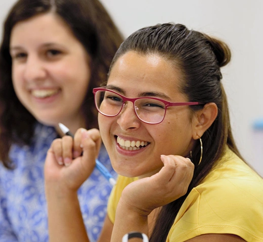 Two female students in classroom, smiling