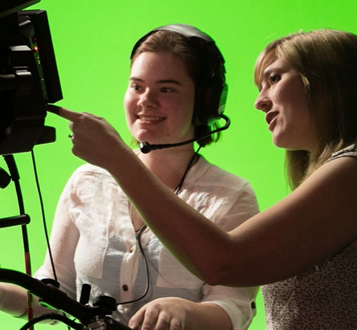 students with a camera in front of a green screen