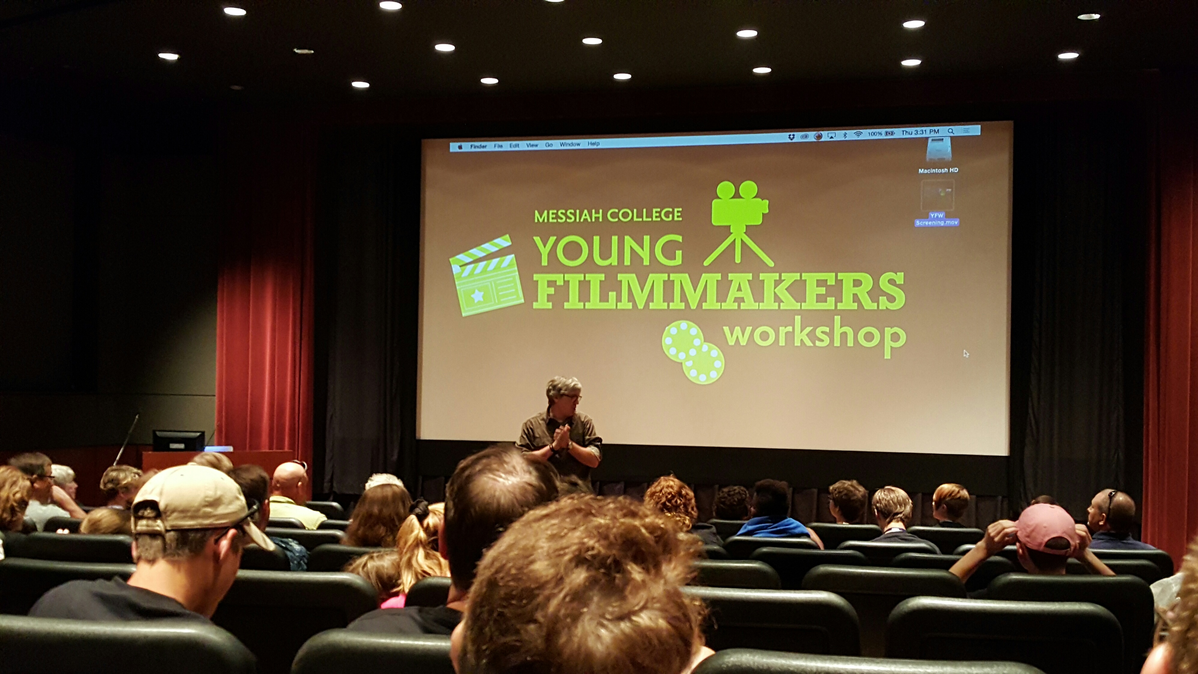 A photo of a film workshop at Messiah University, featuring an instructor speaking to a group of young filmmakers in a theater setting.